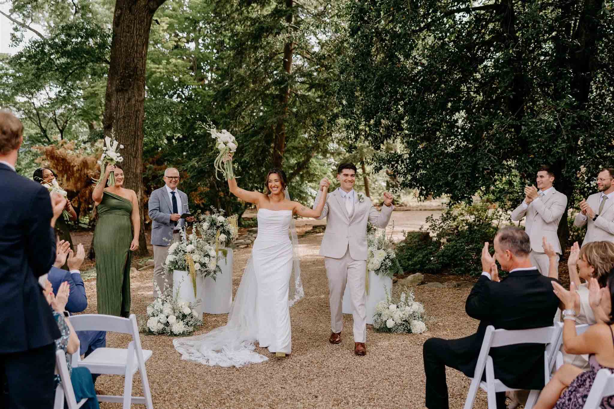 A couple exchanging vows in a picturesque garden setting, surrounded by towering rock formations and lush greenery.
