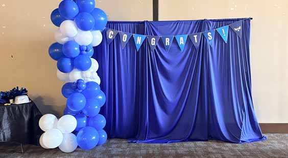 A blue and white photo booth decorated with colorful balloons, inviting guests to take fun pictures.