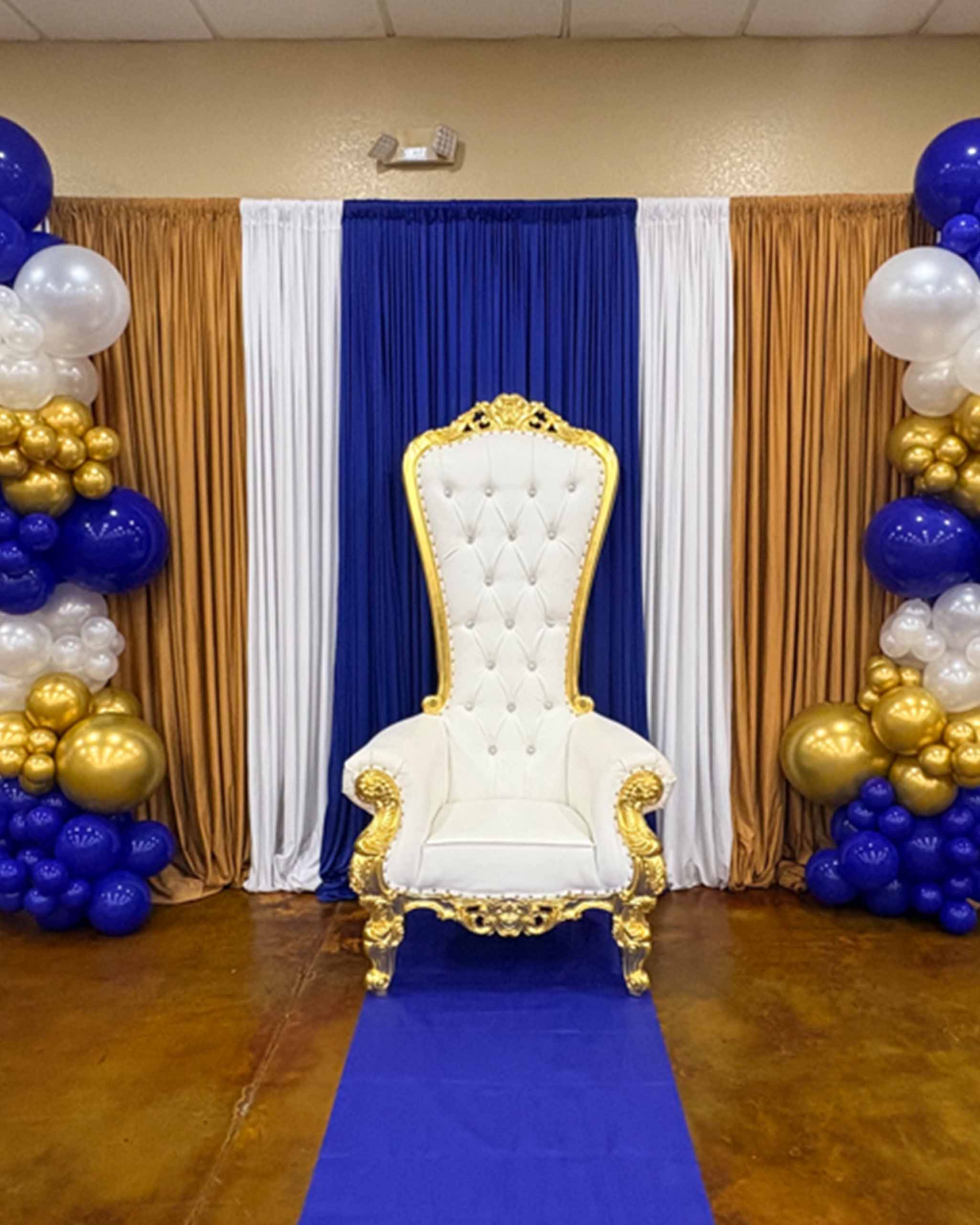 A royal throne adorned with blue and gold balloons, symbolizing celebration and grandeur