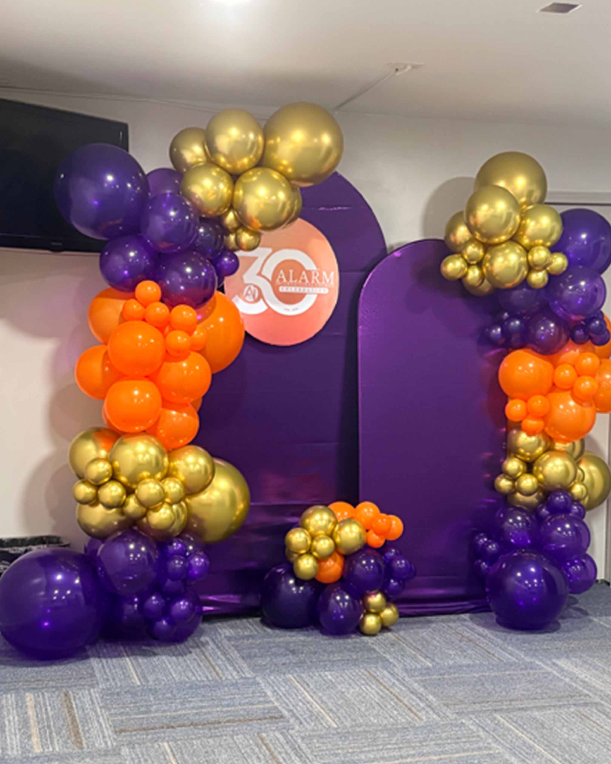 A vibrant arch made of purple and gold balloons, creating a festive atmosphere for an event